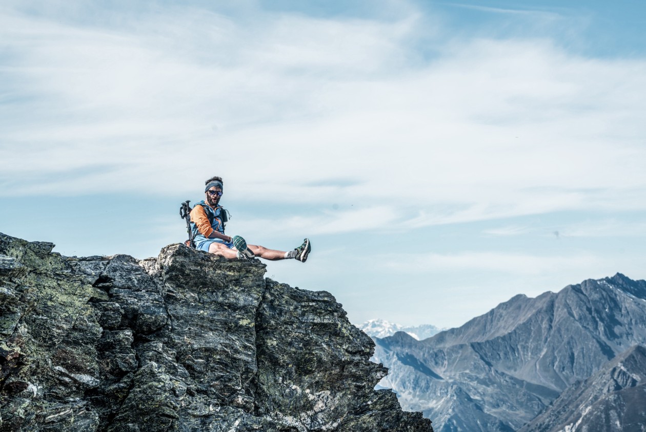 Giovane escursionista seduto sulla cima con vista panoramica sulle montagne dell’Alto Adige – vacanza attiva al Panoramic Lotsch