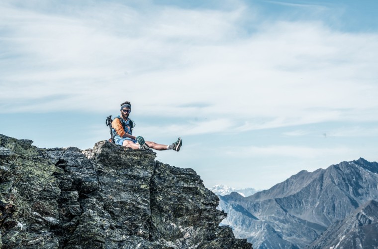 Junger Wanderer sitzt entspannt am Gipfel und genießt den weiten Ausblick über die Bergwelt in Südtirol – aktiver Urlaub im Hotel Panoramic Lotsch