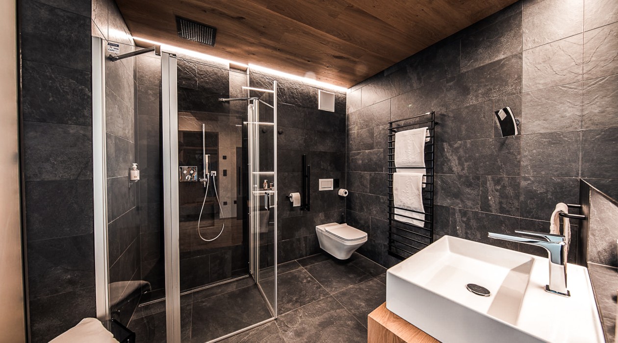 Ruhiges Badezimmer mit Regendusche und Design-Waschbecken Modernes, ruhig gelegenes Badezimmer im Hotel Panoramic Lotsch mit Regendusche und stilvollen Details