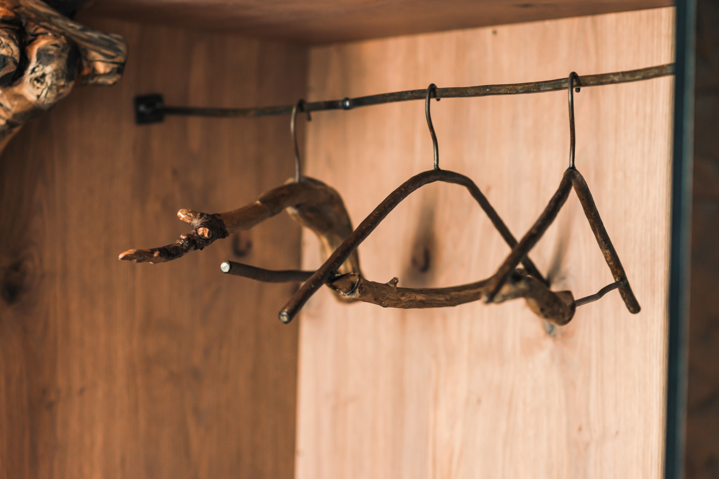 Rustic wooden coat hangers made from branches in the wardrobe of Hotel Panoramic Lotsch, Sarntal – handcrafted detail with a local and natural touch.