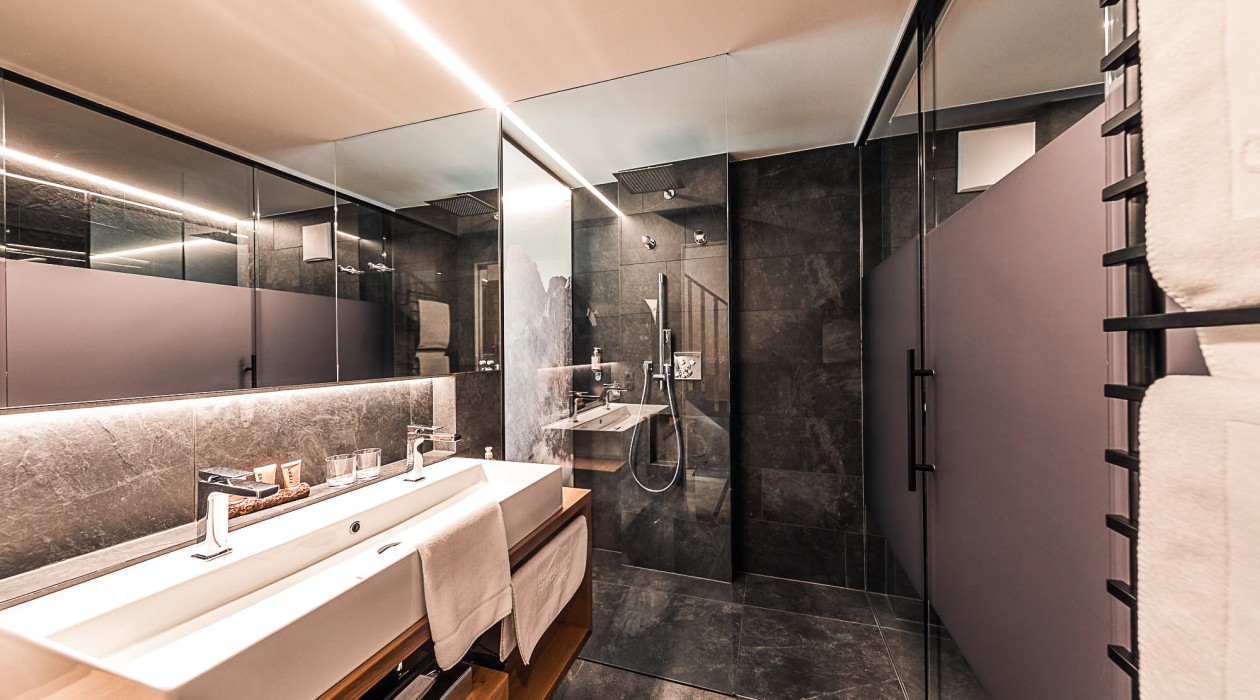 Modern bathroom in the Lotsch Suite at Hotel Panoramic Lotsch, Sarntal – stylish design with double sink, rain shower and high-quality natural materials in a quiet atmosphere.