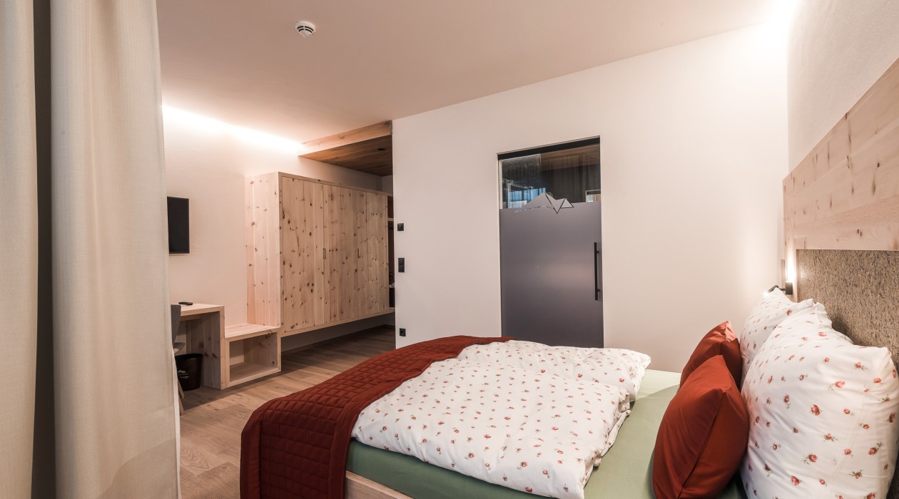 Modernes Doppelzimmer mit großem Fenster, Balkon, Holzfußboden und naturbelassenem Zirbenholzbett – Panoramic Lotsch, Südtirol