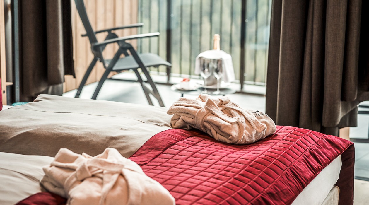 Wellness & Ruhe im Hotel Panoramic Lotsch – Blick auf Terrasse im Sarntal Ruhiger Rückzugsort im Hotel Panoramic Lotsch: Bett mit Bademänteln und Aussicht ins Sarntal – perfekt für aktive Genießer und Wellnessurlaub in Südtirol.