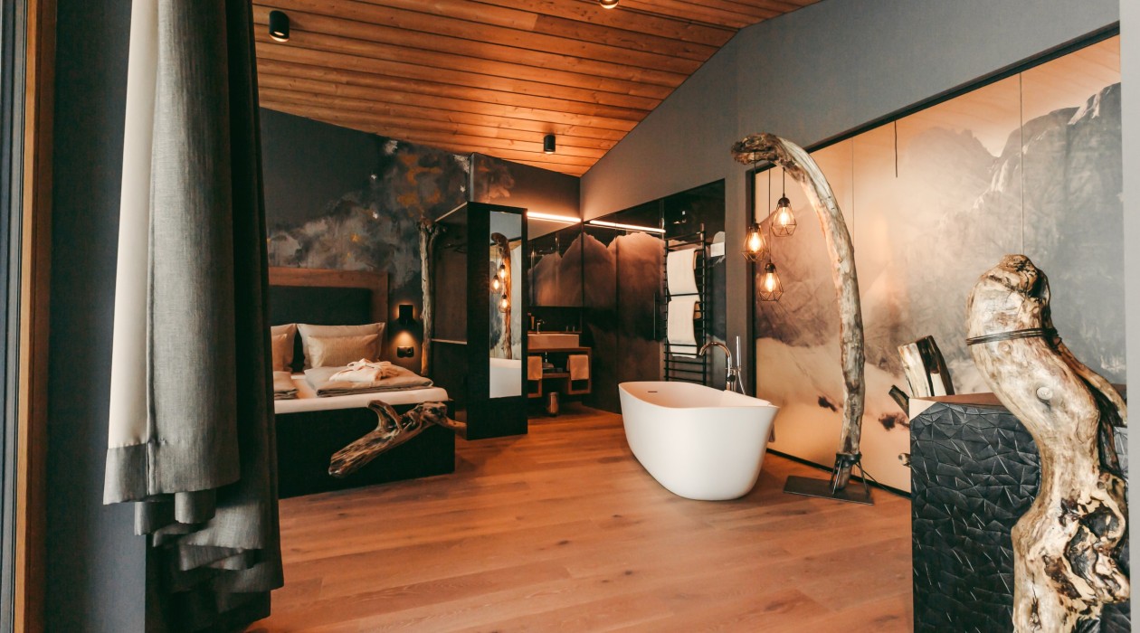 Designsuite mit Badewanne und Wildholz – Hotel Panoramic Lotsch, Sarntal Lotsch Suite mit freistehender Badewanne, Wildholz-Elementen, Designleuchten und Panoramowand – natürliche Materialien und ruhiges Ambiente im Hotel Panoramic Lotsch, Sarntal.