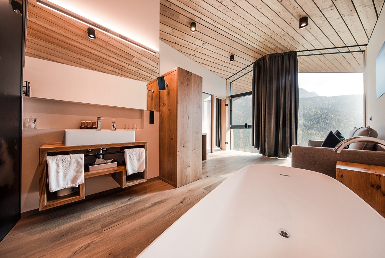 Freistehende Badewanne mit Ausblick in der Lotsch Suite im Hotel Panoramic Lotsch, Sarntal – natürliches Holzdesign, große Fensterfront und ruhige Wellness-Atmosphäre in Südtirol.