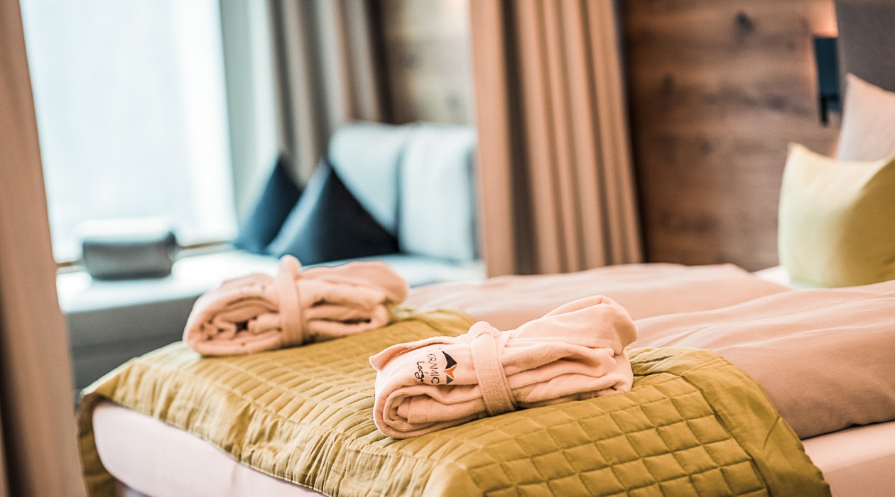 Two bathrobes on a double bed at Hotel Panoramic Lotsch, cozy room with quiet setting in Sarntal, South Tyrol.
