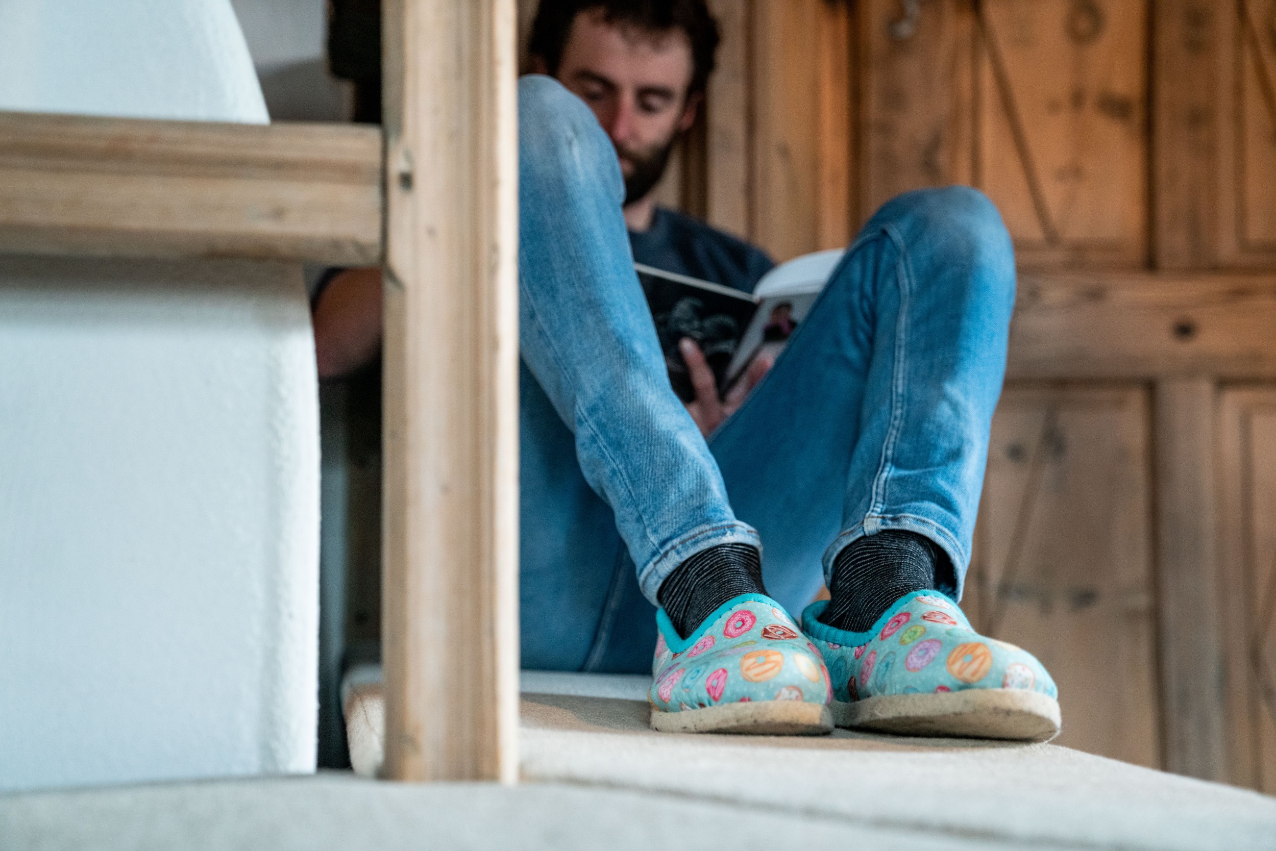 Gast entspannt in bequemen Hausschuhen und liest ein Buch in der gemütlichen Holzstube des Hotels Panoramic Lodge, Sarntal – Wohlfühlmoment in Südtirol.