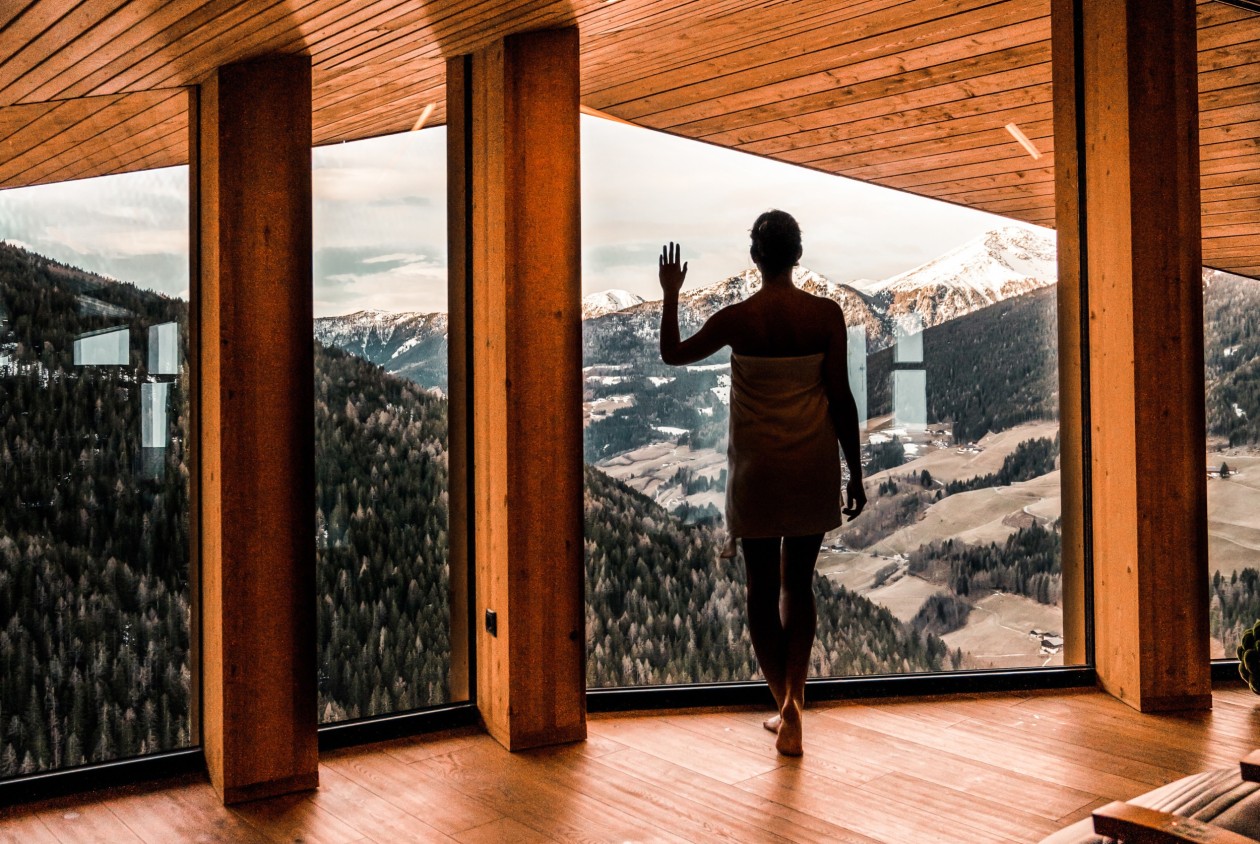 Woman enjoying the view of the snowy mountain landscape from the panoramic wellness area at Hotel Panoramic Lotsch in the Sarentino Valley – relaxation with a view in South Tyrol.