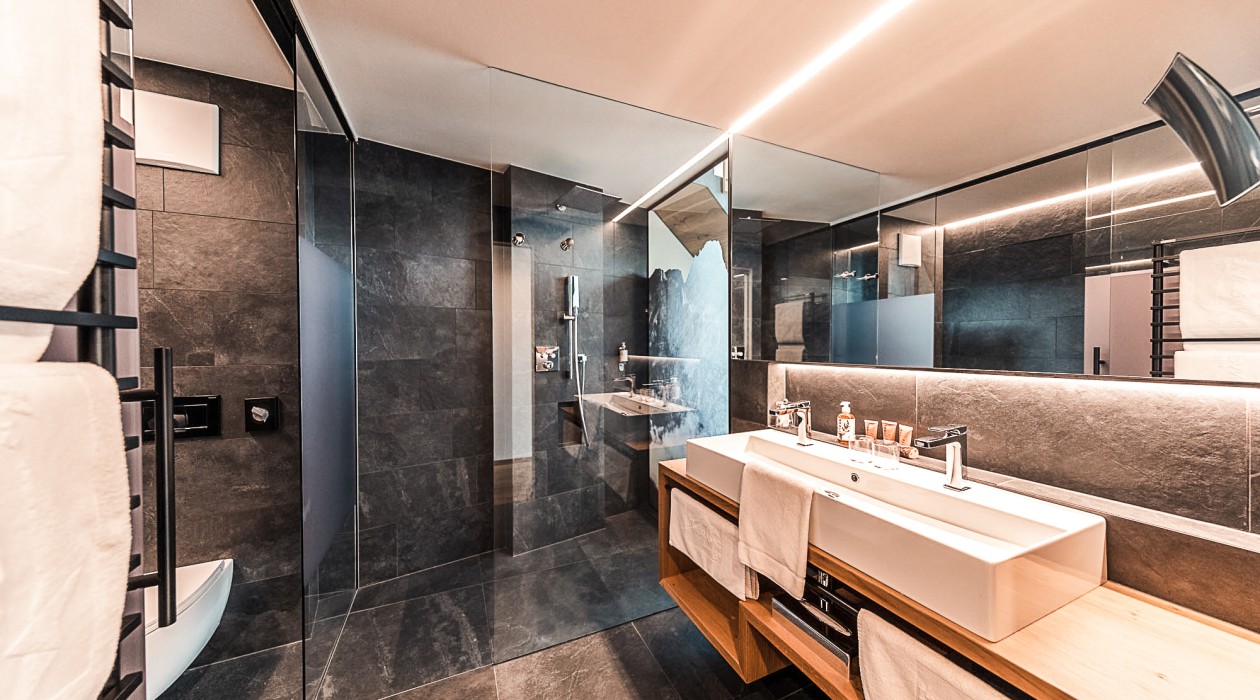 Hochwertiges Bad für entspannte Momente – Wellnessurlaub im Hotel Panoramic Lotsch in Südtirol Modernes Badezimmer im Hotel Panoramic Lotsch mit Doppelwaschbecken und Walk-in-Dusche – ideal für einen aktiven und ruhigen Wellnessurlaub im Sarntal.