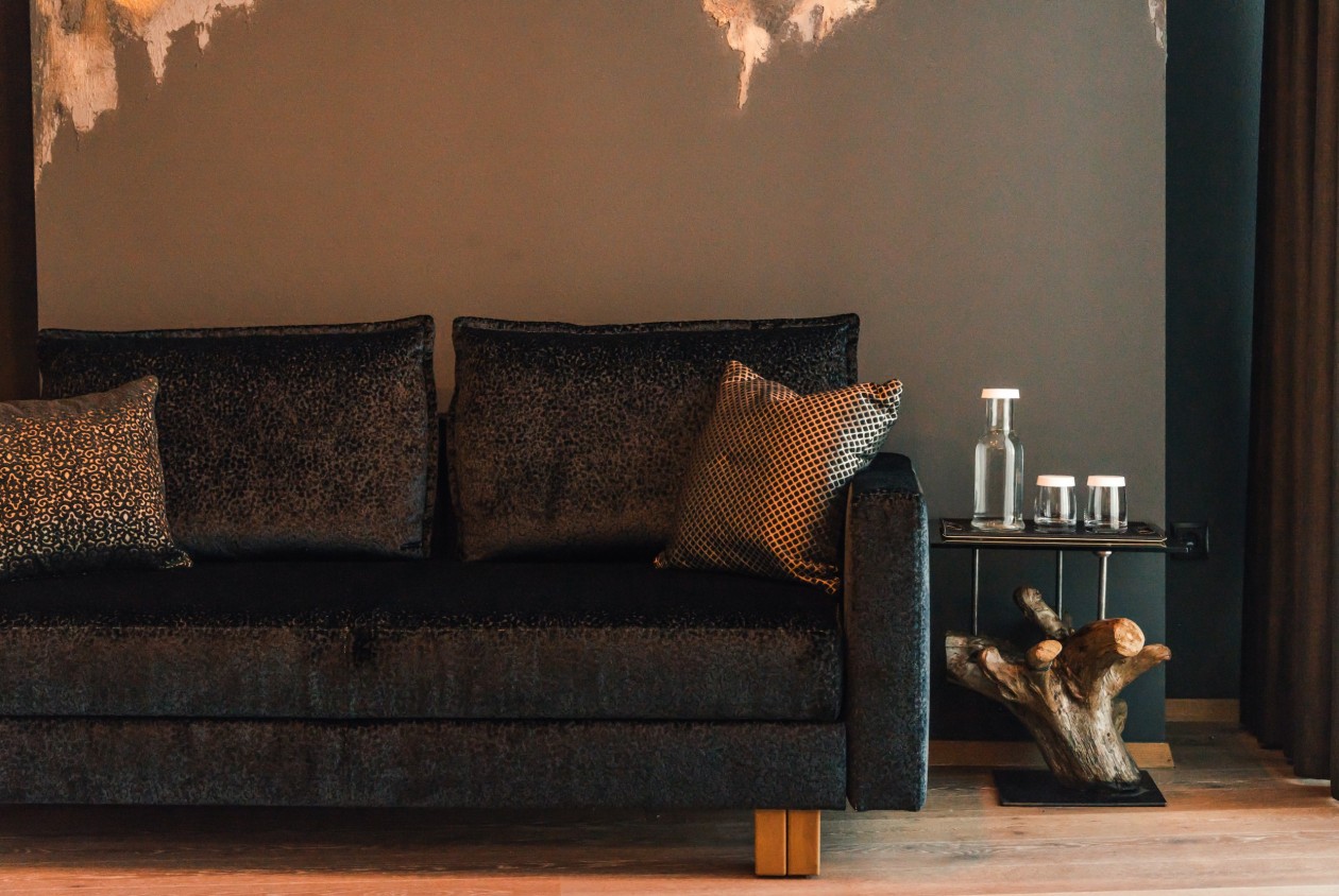 Designsofa mit dekorativen Kissen und Beistelltisch aus Naturholz im Hotel Panoramic Lotsch, Sarntal – stilvolles Detail für eine ruhige Wohnatmosphäre in Südtirol.