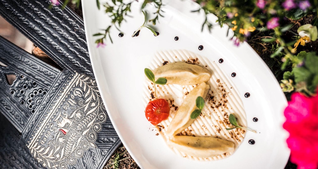 Schlutzkrapfen aus Südtirol – regionale Küche im Hotel Panoramic Lotsch Fein angerichtete Südtiroler Schlutzkrapfen mit Tomate und Kräutern, serviert auf edlem Porzellanteller – kulinarische Tradition im Hotel Panoramic Lotsch, Sarntal.