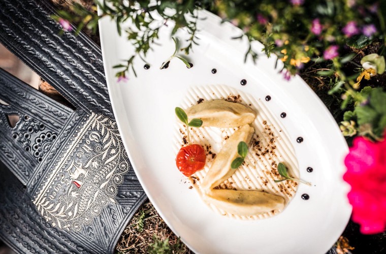 Schlutzkrapfen della tradizione – cucina regionale all’Hotel Panoramic Lotsch Schlutzkrapfen altoatesini finemente impiattati con pomodorino ed erbe aromatiche su piatto elegante – tradizione culinaria all’Hotel Panoramic Lotsch in Val Sarentino.