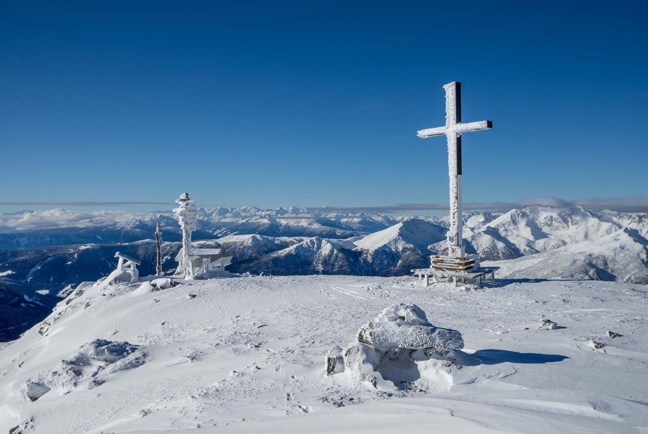 Verschneiter Gipfel mit Kreuz und Dolomitenblick – aktives Wintererlebnis im Sarntal bei Hotel Panoramic Lotsch, Südtirol