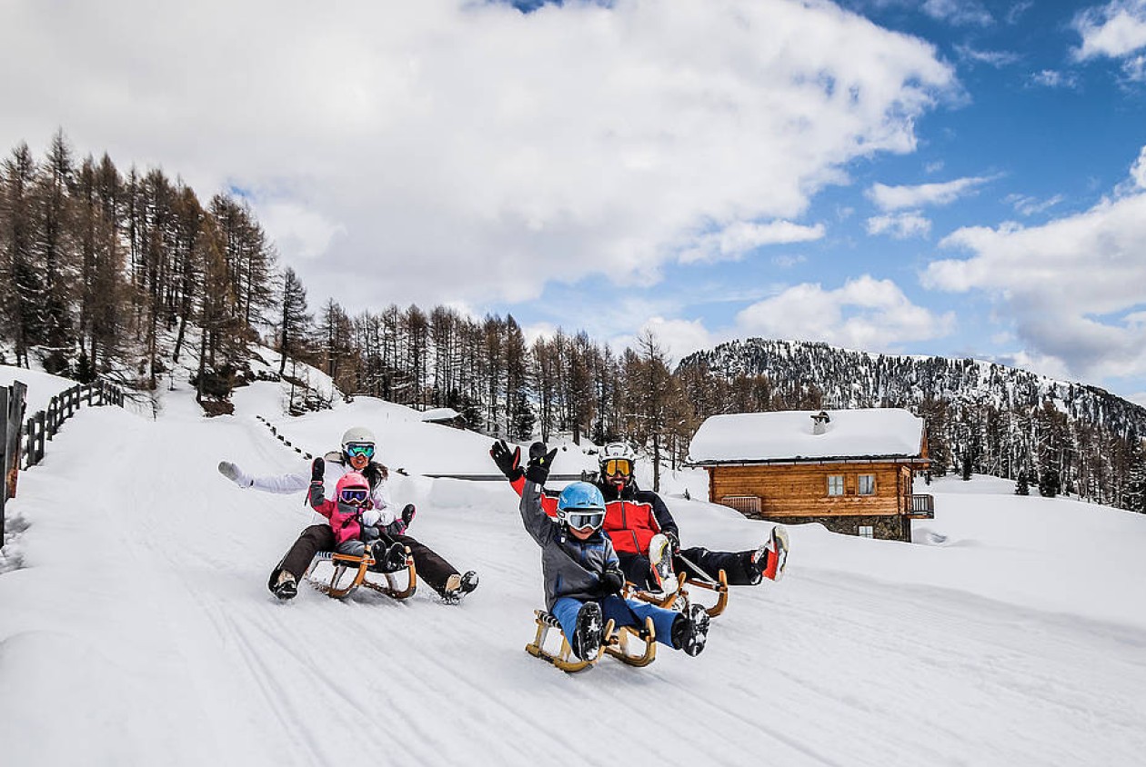 Familie beim Rodeln auf einer Winterrodelbahn im Sarntal – aktiver Winterurlaub in Südtirol mit Spaß und Natur