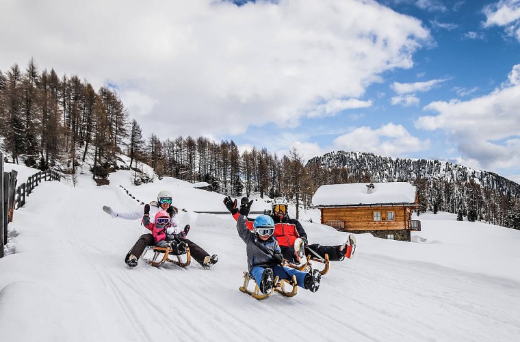 Familie beim Rodeln auf einer Winterrodelbahn im Sarntal – aktiver Winterurlaub in Südtirol mit Spaß und Natur