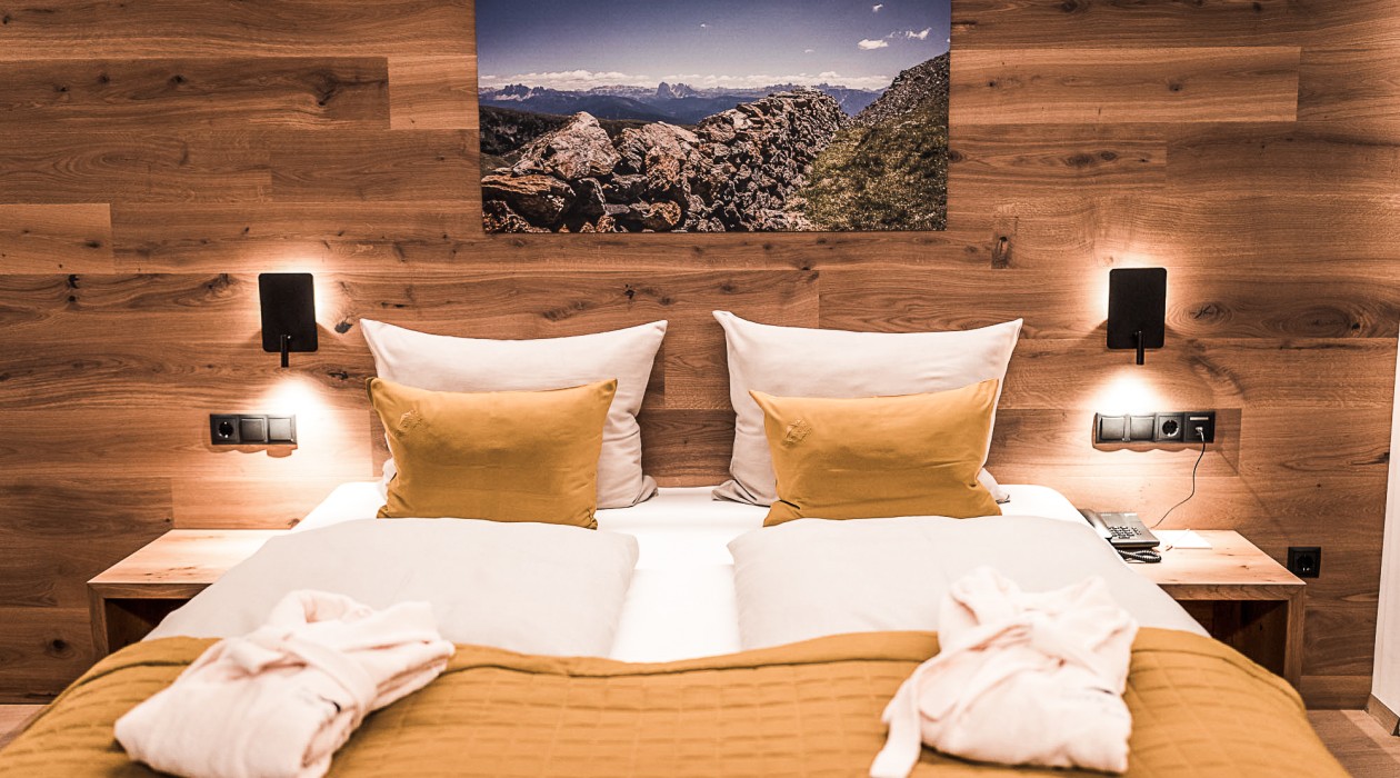 Stilvoll eingerichtetes Doppelzimmer mit Holzwand, Naturbettwäsche und Landschaftsbild – gemütlich & ruhig im Hotel Panoramic Lotsch, Südtirol