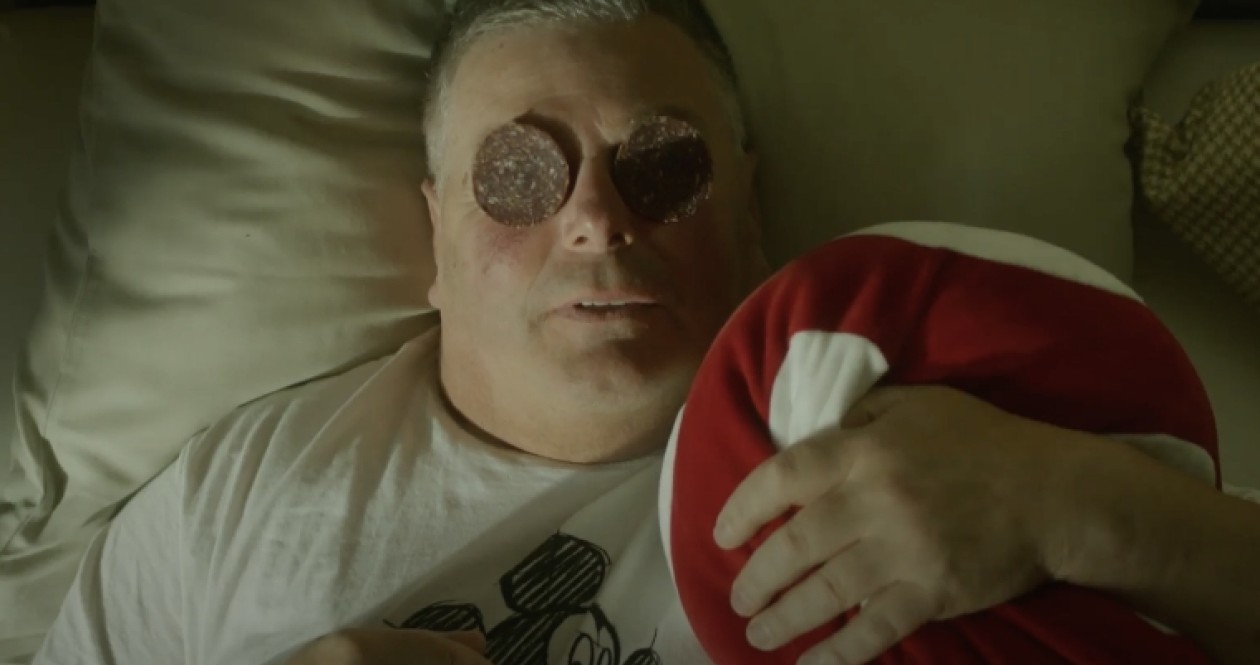 Mann mit Salamischeiben auf den Augen im Bett – humorvoller Moment im Hotel Panoramic Lotsch als augenzwinkernde Hommage an Südtiroler Wellness