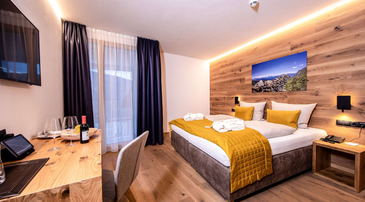 Modernes Doppelzimmer mit Balkon, Eichenholz-Möbeln und warmem Licht – ruhige Lage im Hotel Panoramic Lotsch, Sarntal, Südtirol