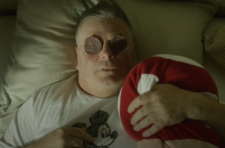 Mann mit Salamischeiben auf den Augen im Bett – humorvoller Moment im Hotel Panoramic Lotsch als augenzwinkernde Hommage an Südtiroler Wellness